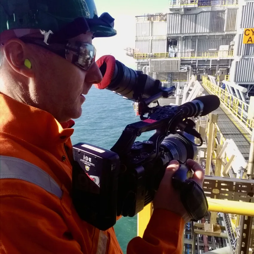 Elliot Hornell operating a shoulder-mounted camera offshore in protective equipment